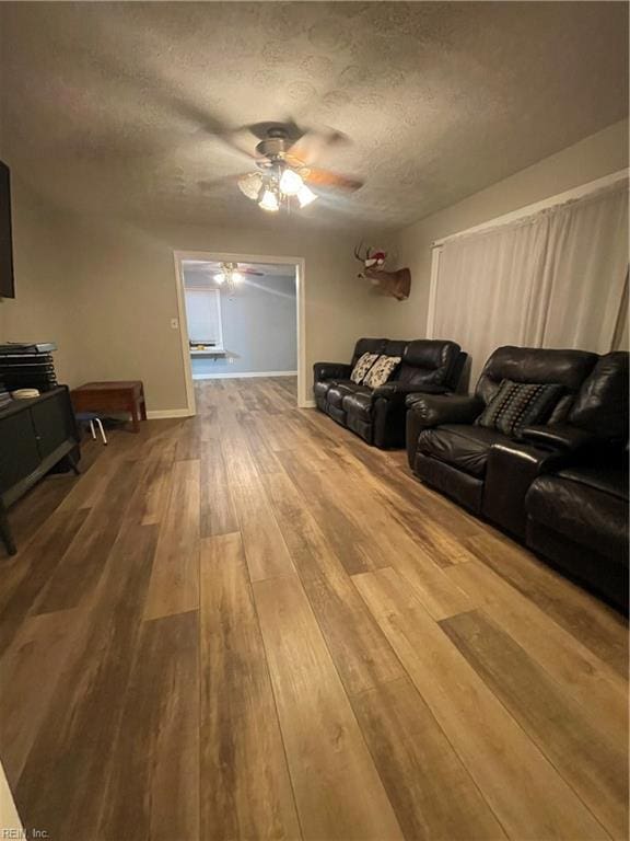 living room with a textured ceiling, hardwood / wood-style flooring, and ceiling fan