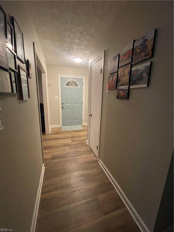 corridor with hardwood / wood-style flooring and a textured ceiling