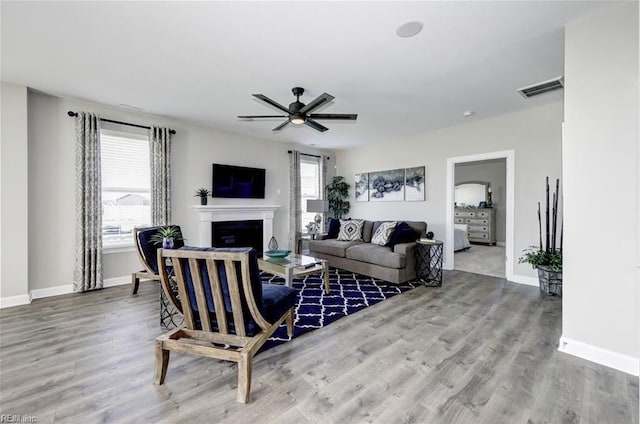 living room featuring ceiling fan, wood-type flooring, and a wealth of natural light