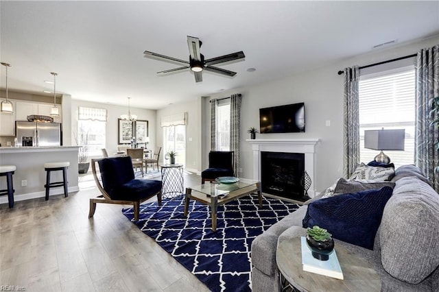 living room featuring dark hardwood / wood-style floors, ceiling fan with notable chandelier, and a wealth of natural light