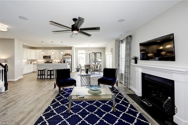 living room featuring ceiling fan with notable chandelier and hardwood / wood-style flooring