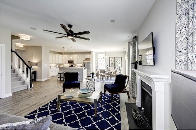 living room with ceiling fan with notable chandelier and hardwood / wood-style flooring