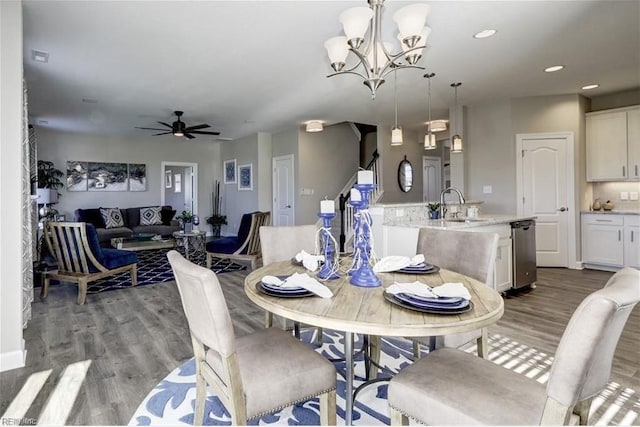 dining space with sink, ceiling fan with notable chandelier, and light hardwood / wood-style flooring