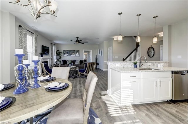 dining area featuring sink, ceiling fan with notable chandelier, and light wood-type flooring