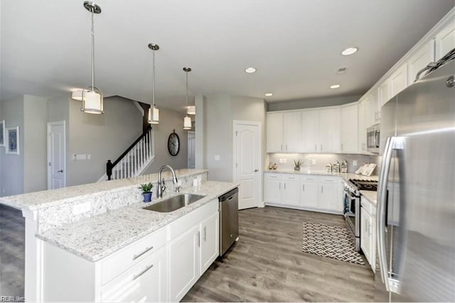 kitchen with sink, stainless steel appliances, white cabinetry, and an island with sink