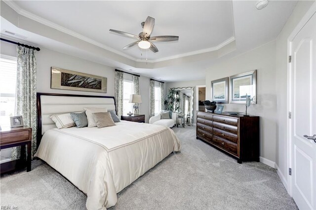 carpeted bedroom featuring a raised ceiling, ceiling fan, and ornamental molding