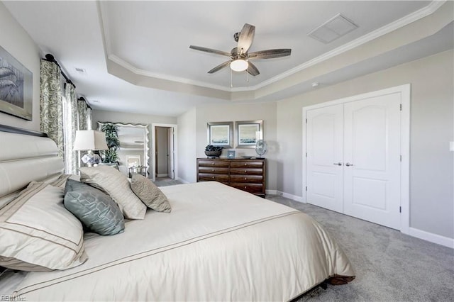 carpeted bedroom featuring ceiling fan, a closet, ornamental molding, and a tray ceiling