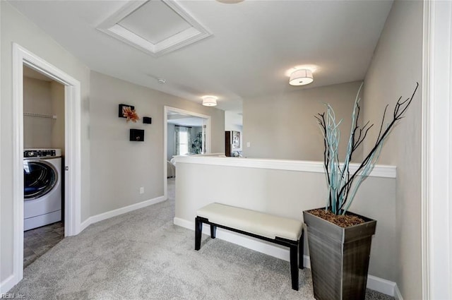 hallway with washer / dryer and light colored carpet