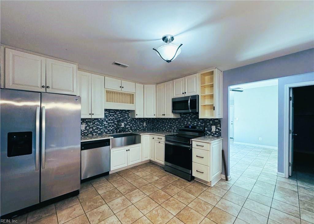 kitchen featuring sink, light tile patterned floors, tasteful backsplash, white cabinetry, and stainless steel appliances