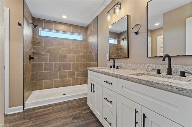 bathroom with hardwood / wood-style floors, vanity, and tiled shower