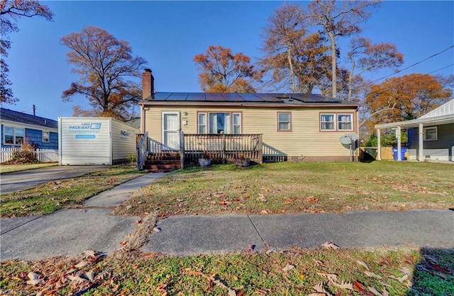 view of front of property with a front yard, solar panels, and a wooden deck