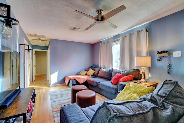 living room featuring ceiling fan, light hardwood / wood-style floors, and a textured ceiling