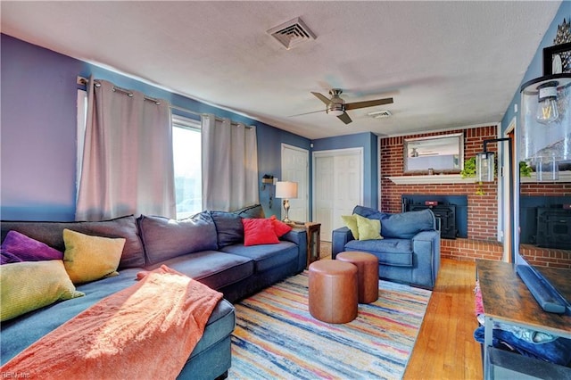 living room featuring ceiling fan, light hardwood / wood-style floors, and a wood stove