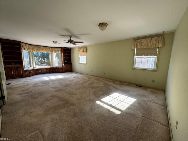 spare room featuring ceiling fan, plenty of natural light, and light colored carpet