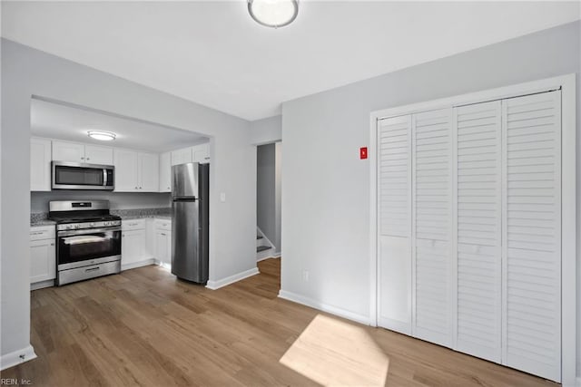 kitchen with white cabinets, light wood-type flooring, and appliances with stainless steel finishes