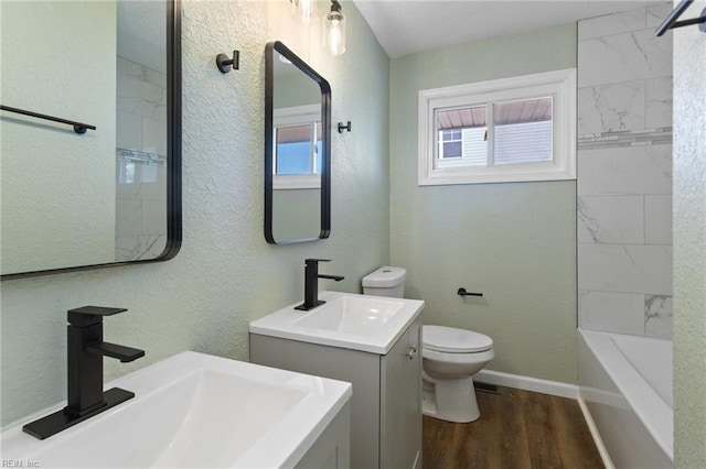 full bathroom featuring vanity, toilet, wood-type flooring, and tiled shower / bath combo