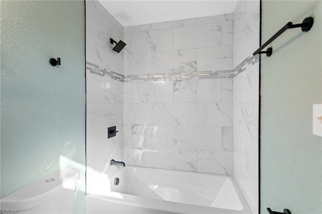 bathroom with toilet and tiled shower / bath