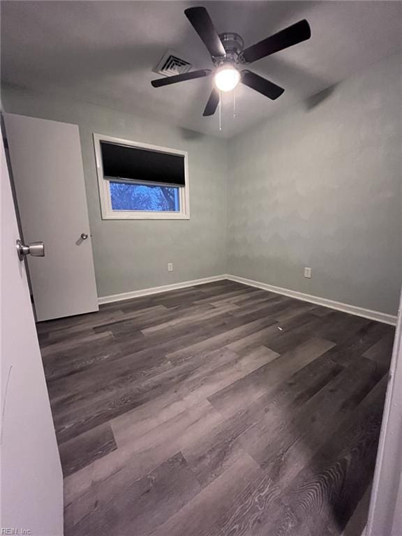 unfurnished bedroom featuring dark wood-style floors, visible vents, baseboards, and a ceiling fan