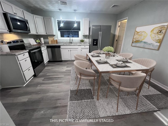 kitchen featuring visible vents, dark wood finished floors, white cabinets, stainless steel appliances, and a sink