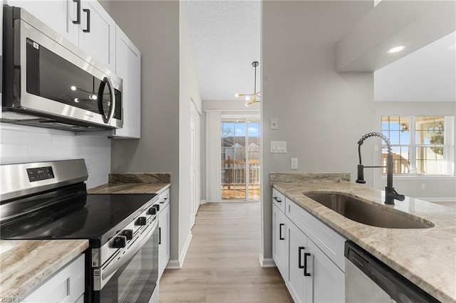 kitchen featuring appliances with stainless steel finishes, white cabinetry, a wealth of natural light, and sink