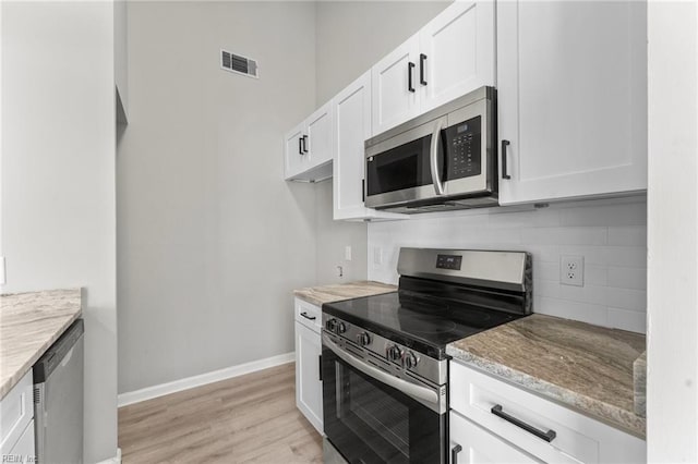 kitchen featuring backsplash, white cabinets, light hardwood / wood-style flooring, light stone countertops, and appliances with stainless steel finishes