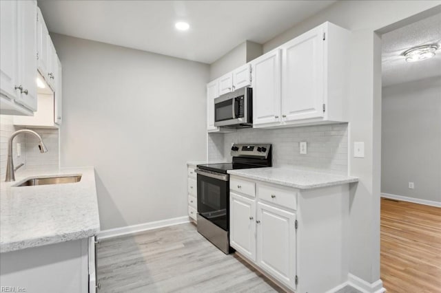 kitchen with light stone counters, sink, white cabinetry, and stainless steel appliances