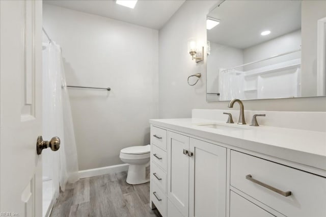 bathroom with toilet, hardwood / wood-style floors, vanity, and walk in shower