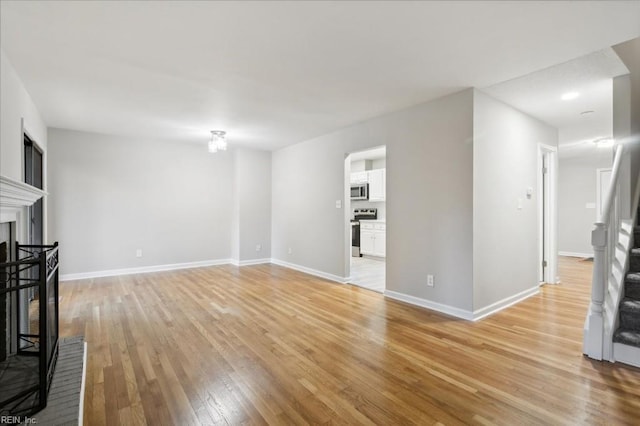 unfurnished living room with a fireplace and light wood-type flooring