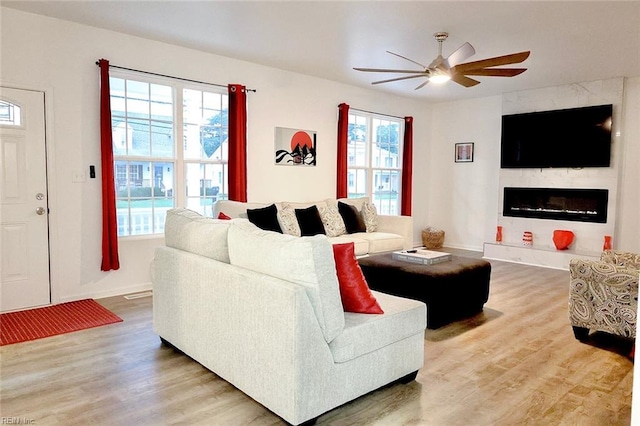 living room featuring ceiling fan, wood-type flooring, and a fireplace