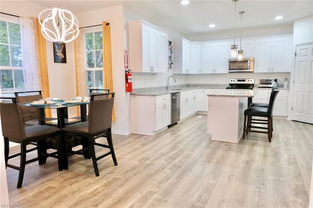 kitchen featuring white cabinetry, a center island, light hardwood / wood-style flooring, pendant lighting, and appliances with stainless steel finishes