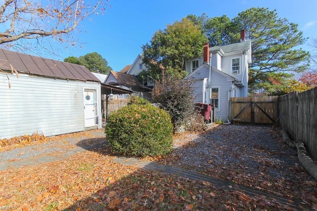 view of side of property featuring an outbuilding, a gate, fence, and a chimney