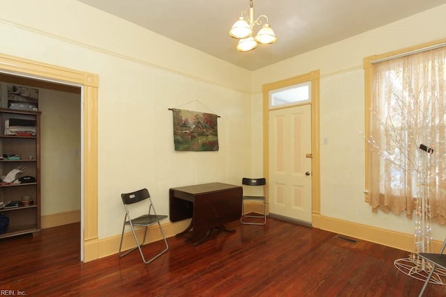 foyer entrance with dark wood-style floors, baseboards, visible vents, and an inviting chandelier