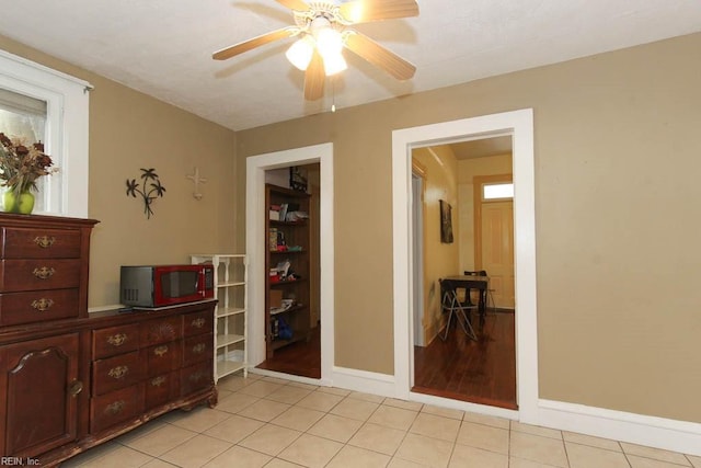 interior space featuring ceiling fan, light tile patterned flooring, and baseboards