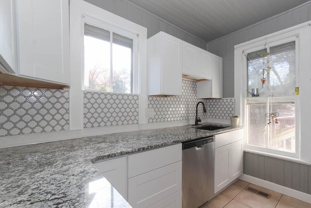 kitchen featuring white cabinets, a sink, stainless steel dishwasher, and light stone countertops