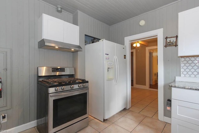 kitchen with light tile patterned floors, exhaust hood, white cabinetry, white fridge with ice dispenser, and stainless steel range with gas stovetop