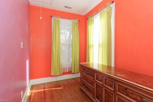 hall with attic access, visible vents, baseboards, and wood finished floors