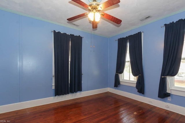 empty room featuring plenty of natural light, wood finished floors, and visible vents