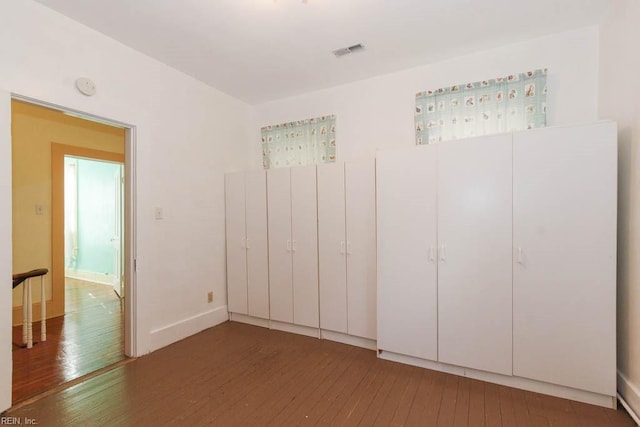 unfurnished bedroom featuring visible vents and dark wood finished floors