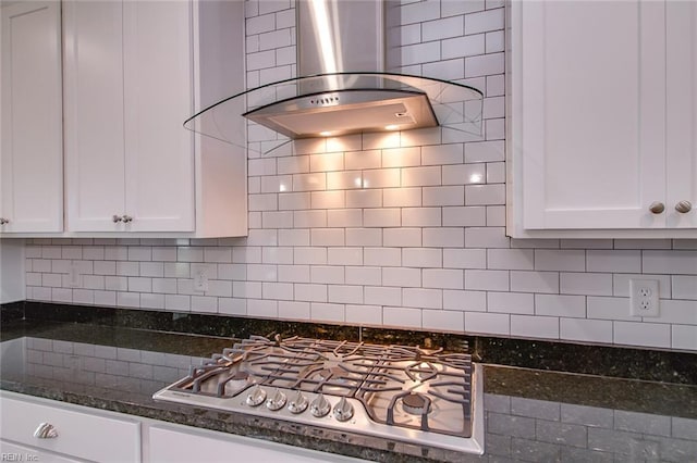 kitchen featuring tasteful backsplash, wall chimney exhaust hood, dark stone countertops, and white cabinets