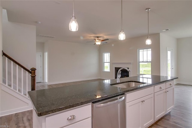 kitchen with pendant lighting, a center island with sink, sink, stainless steel dishwasher, and white cabinetry