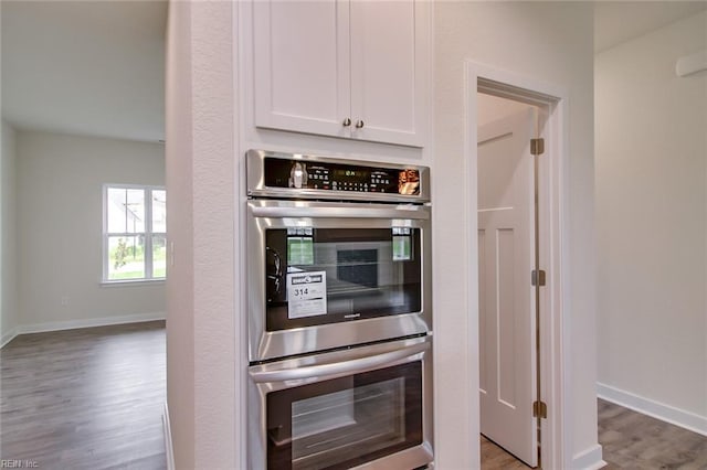 kitchen with wood-type flooring, white cabinetry, and double oven