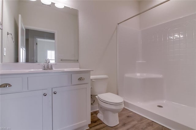 bathroom with hardwood / wood-style flooring, vanity, toilet, and a shower