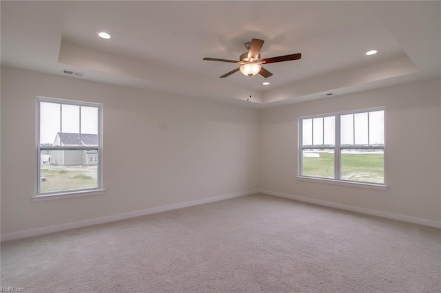 empty room featuring carpet flooring, a tray ceiling, and ceiling fan