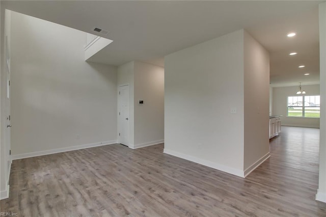 spare room with light hardwood / wood-style floors and a notable chandelier