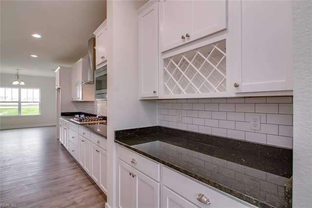 kitchen with dark stone counters, white cabinets, decorative backsplash, appliances with stainless steel finishes, and decorative light fixtures