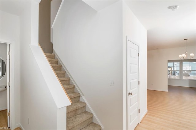 staircase featuring hardwood / wood-style floors and a notable chandelier