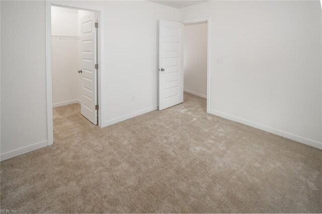 unfurnished bedroom with light carpet, a walk in closet, and a closet