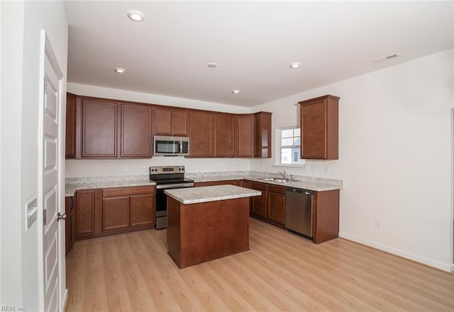 kitchen featuring sink, a kitchen island, stainless steel appliances, and light wood-type flooring