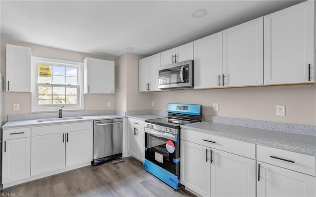 kitchen featuring light wood-type flooring, stainless steel appliances, white cabinetry, and sink