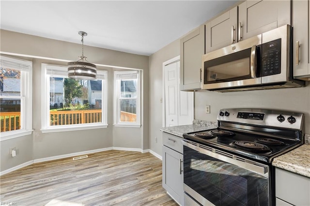 kitchen featuring hanging light fixtures, light hardwood / wood-style flooring, gray cabinets, light stone countertops, and appliances with stainless steel finishes